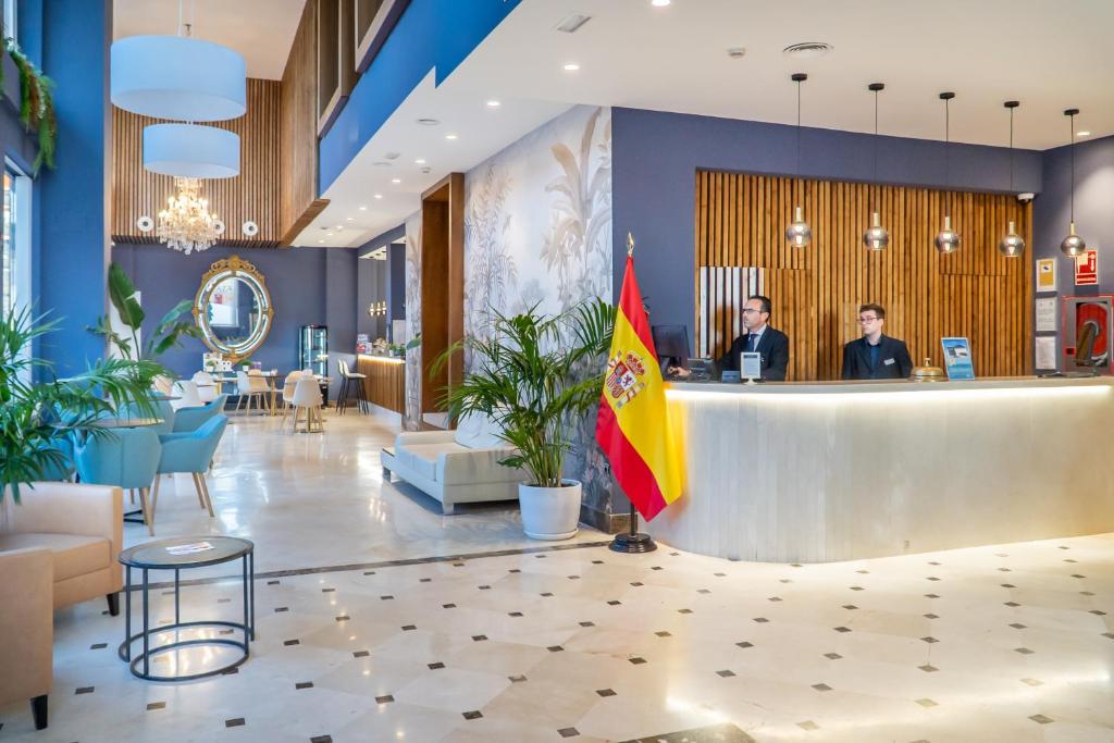 a lobby of a hotel with two people at a counter at Hotel Spa Cádiz Plaza in Cádiz