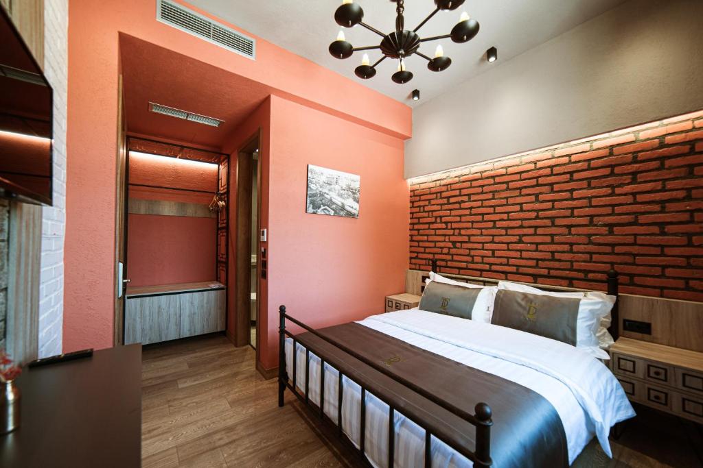 a bedroom with a large bed and a brick wall at Hotel Taverna Devolli in Kuçovë