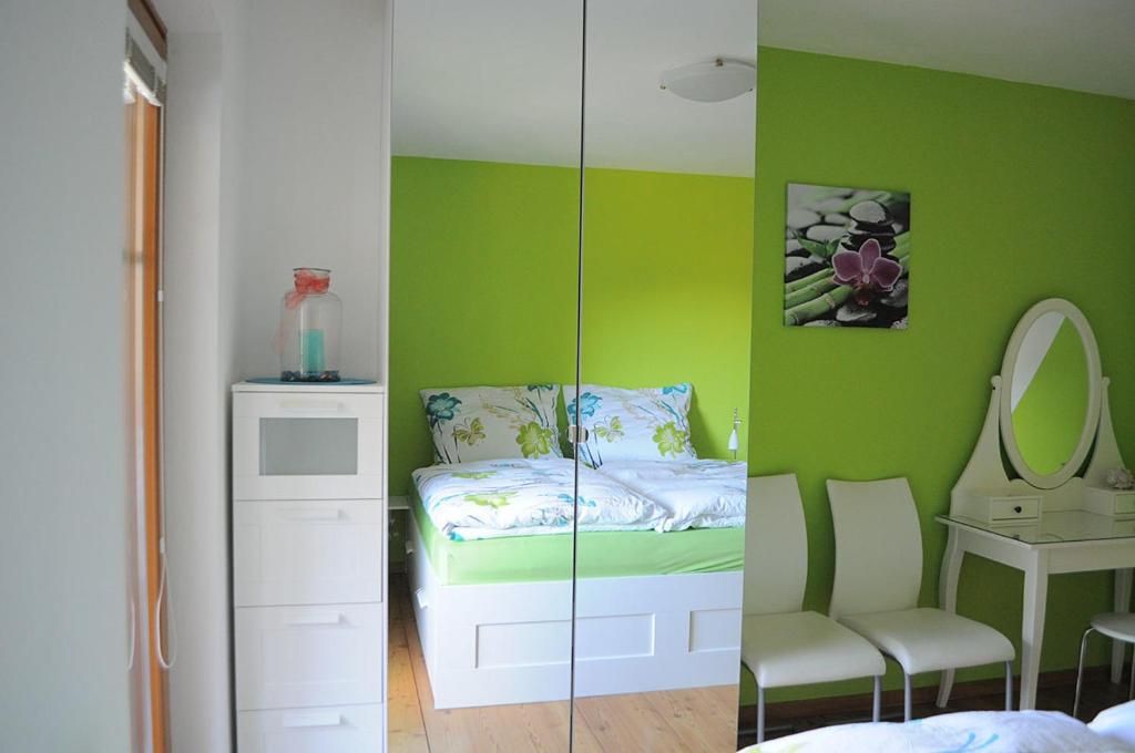 a bedroom with a green wall with a bed and a mirror at Haus Eichhorn Ferienwohnung in Hermagor