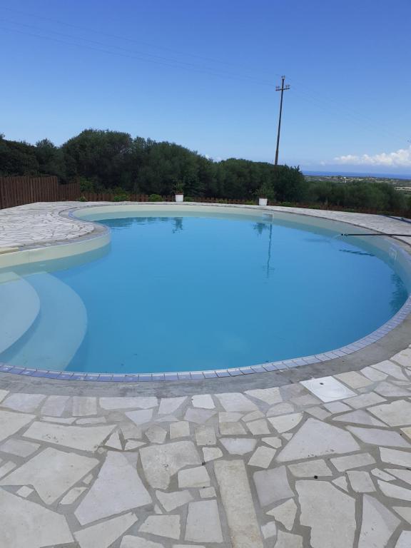 ein großes Schwimmbecken mit blauem Wasser in der Unterkunft agriturismo gli olivastri, appartamento la rosa dei venti con piscina e solarium , vista mare ,climatizzatore ,wifi in Aglientu
