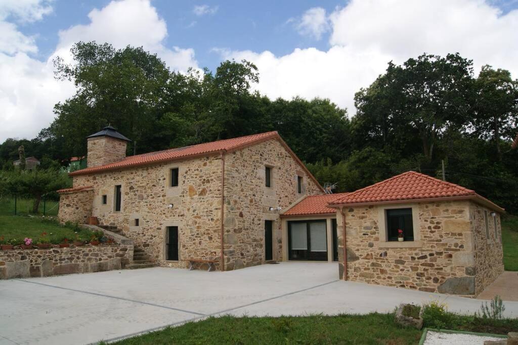 a stone house with a garage in a yard at Casa de Busto in Zas