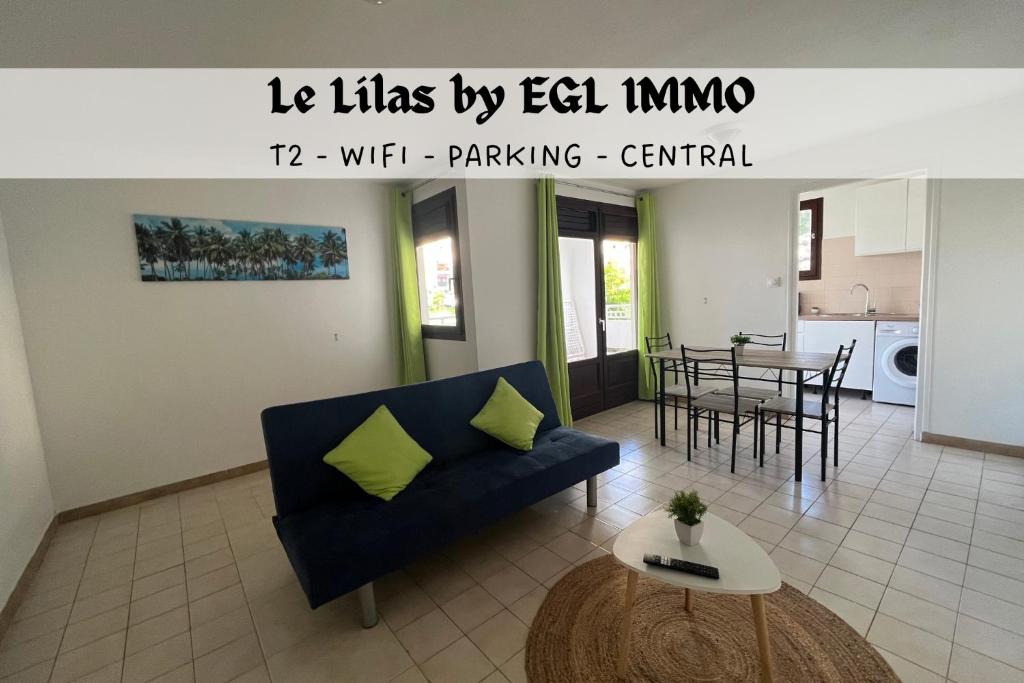 a living room with a blue couch and a table at Le Lilas by EGL IMMO in Ducos
