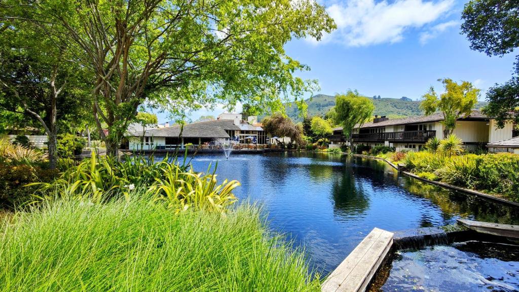 a river with a wooden bridge and some houses at The Quail Lodge in Carmel