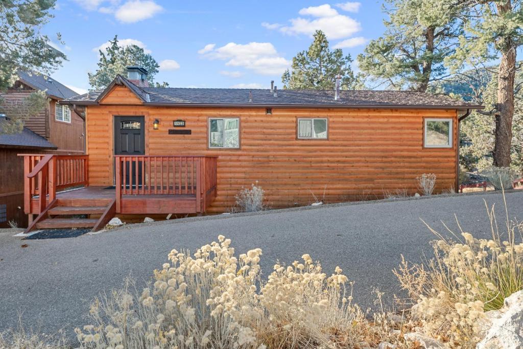 Una cabaña de madera con porche y entrada para coches. en Forest Edge Retreat - Cozy, log cabin with a wood burning fireplace! Pool Table, Foosball and Darts!, en Big Bear City