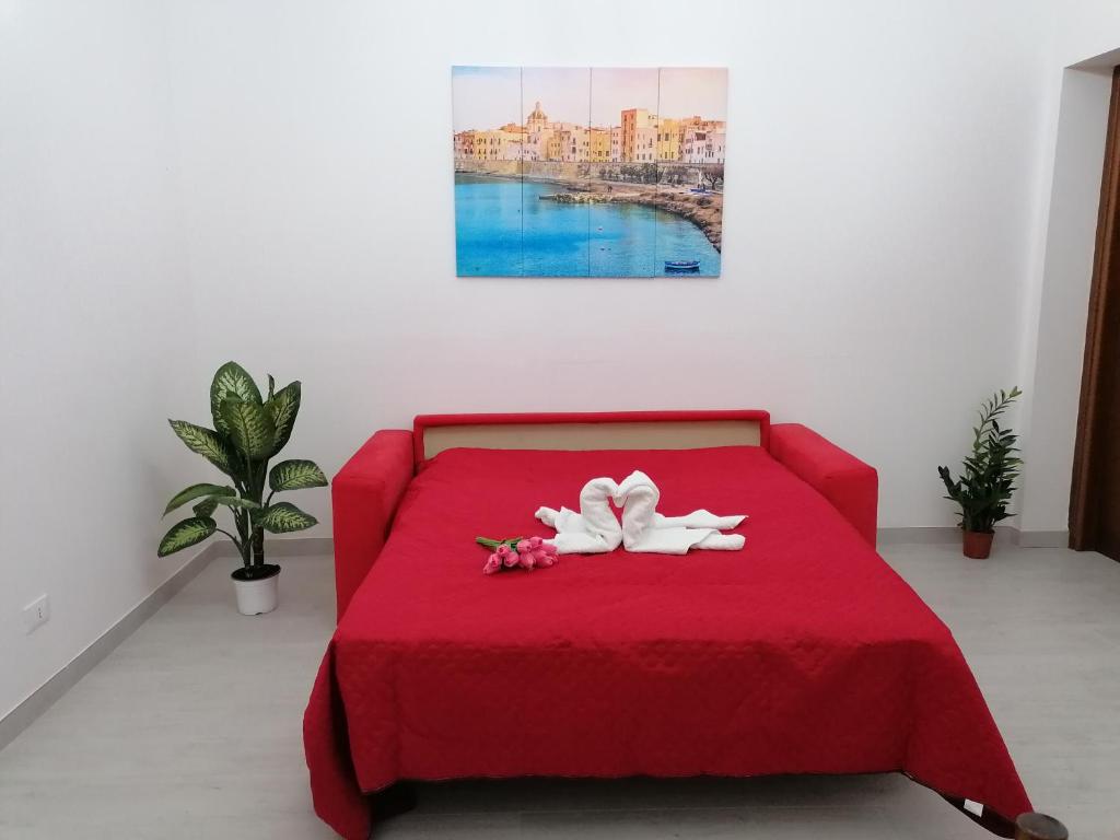 ein rotes Bett mit zwei weißen Handtüchern drauf in der Unterkunft Tulipano in Trapani