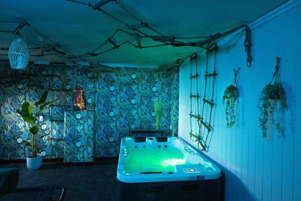 eine Badewanne in einem Zimmer mit blauen Lichtern in der Unterkunft Casawellness améthyste ou jaspe océan avec jacuzzi intérieur in Floreffe