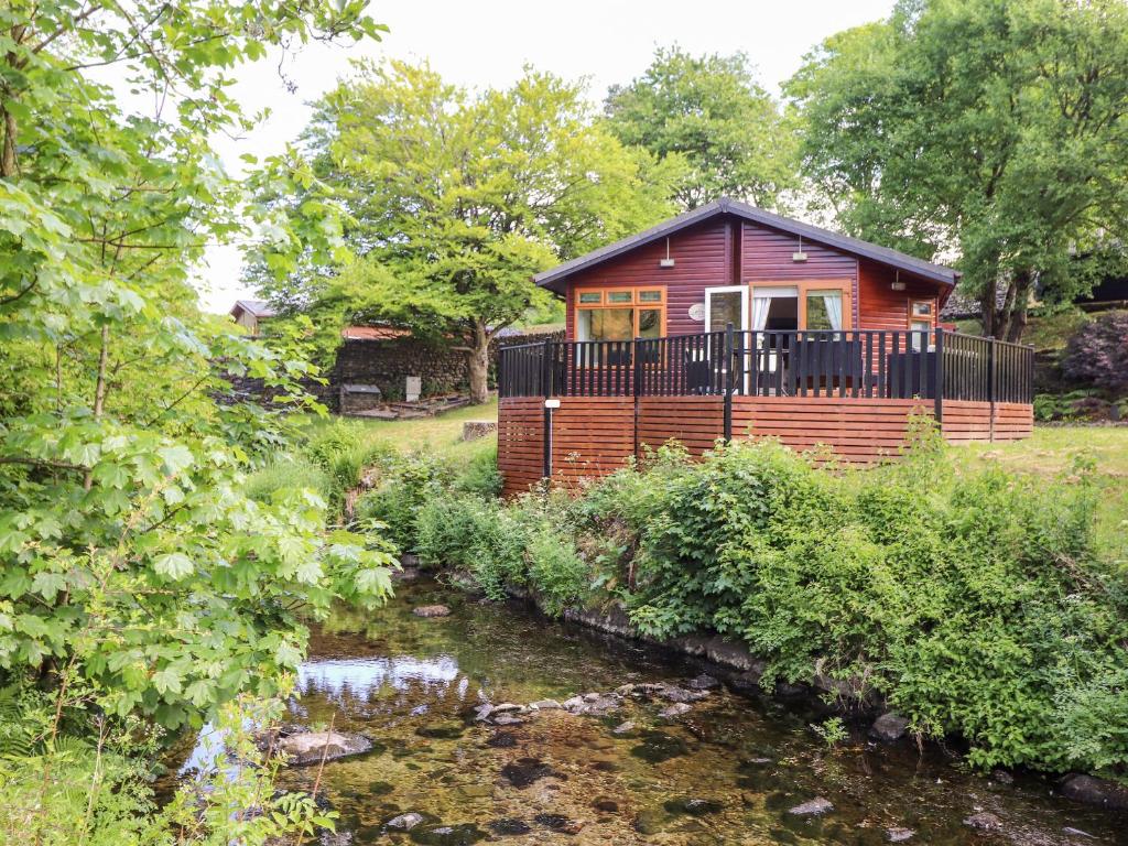 a red cabin with a balcony next to a river at Nutkins Lodge in Windermere