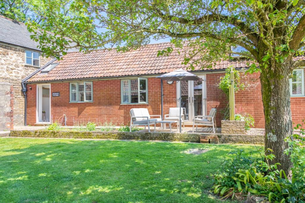 a brick house with a patio and an umbrella at The Granary in Beaminster