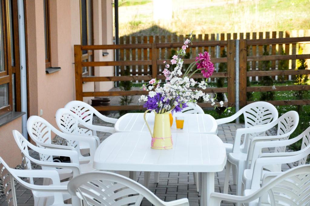 uma mesa branca com cadeiras brancas e flores num pátio em Rekreace na Lipně em Frymburk