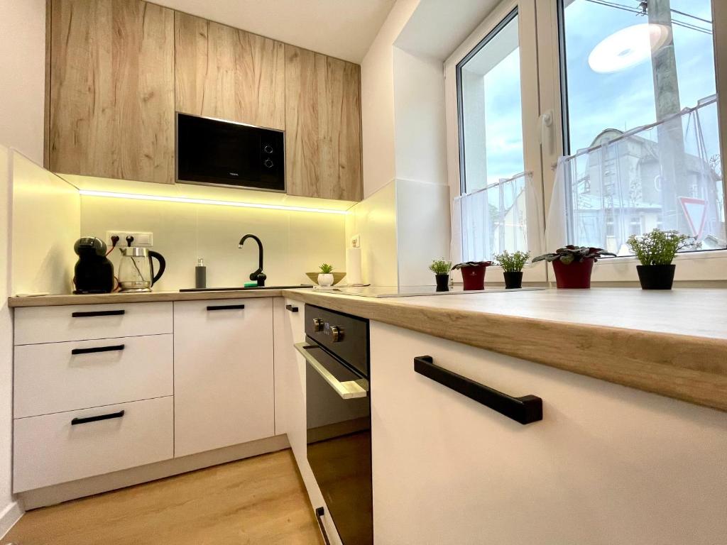 a kitchen with white cabinets and a large window at Mand apartmán in Žilina