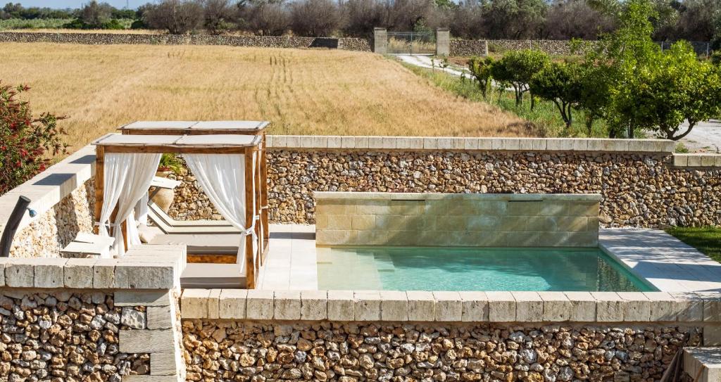 a swimming pool in a stone retaining wall with a spa at Agriturismo Masseria Costarella in Borgagne