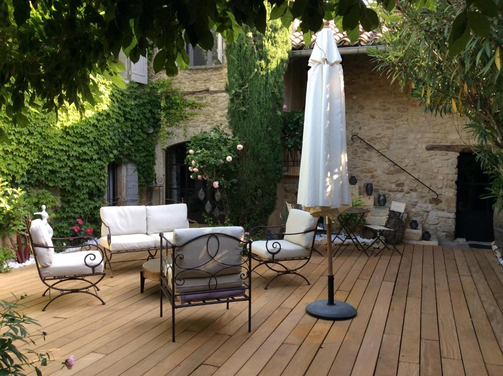 een patio met een parasol, stoelen en een tafel bij La Maiz in Maubec