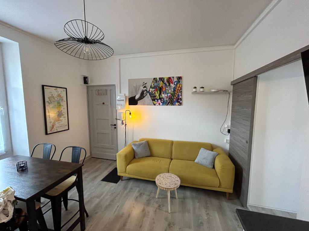 a living room with a yellow couch and a table at Bienvenue au Quai 27 in Épernay