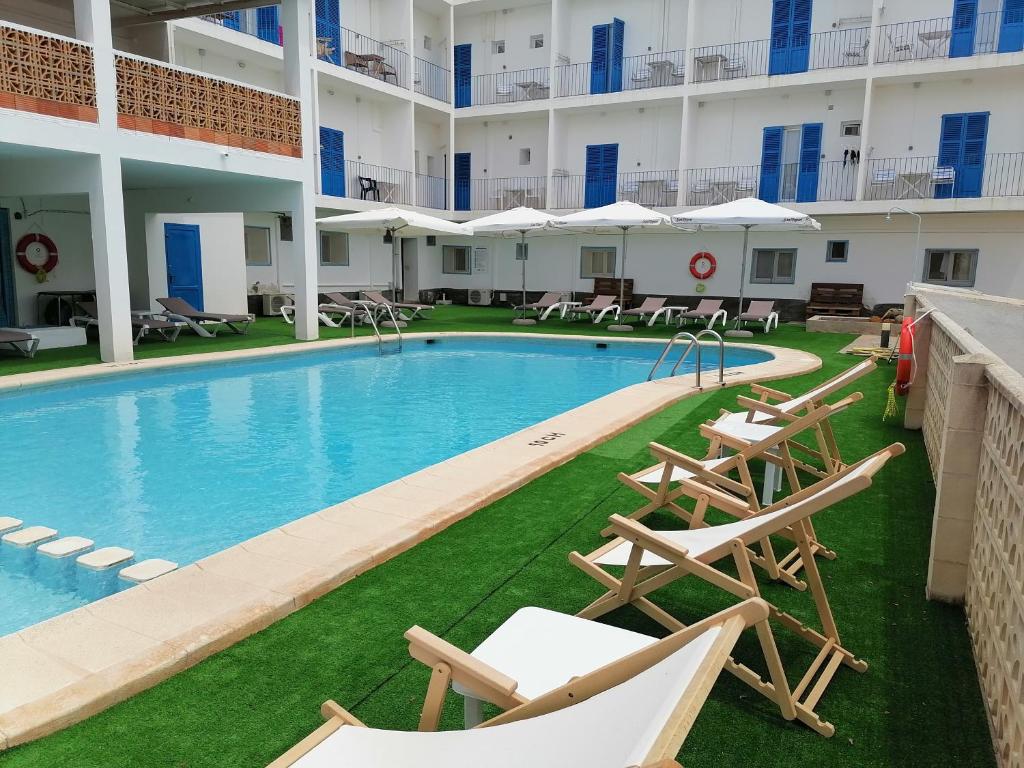 a swimming pool with lounge chairs in a hotel at Hostal Pepe in Sant Ferran de Ses Roques
