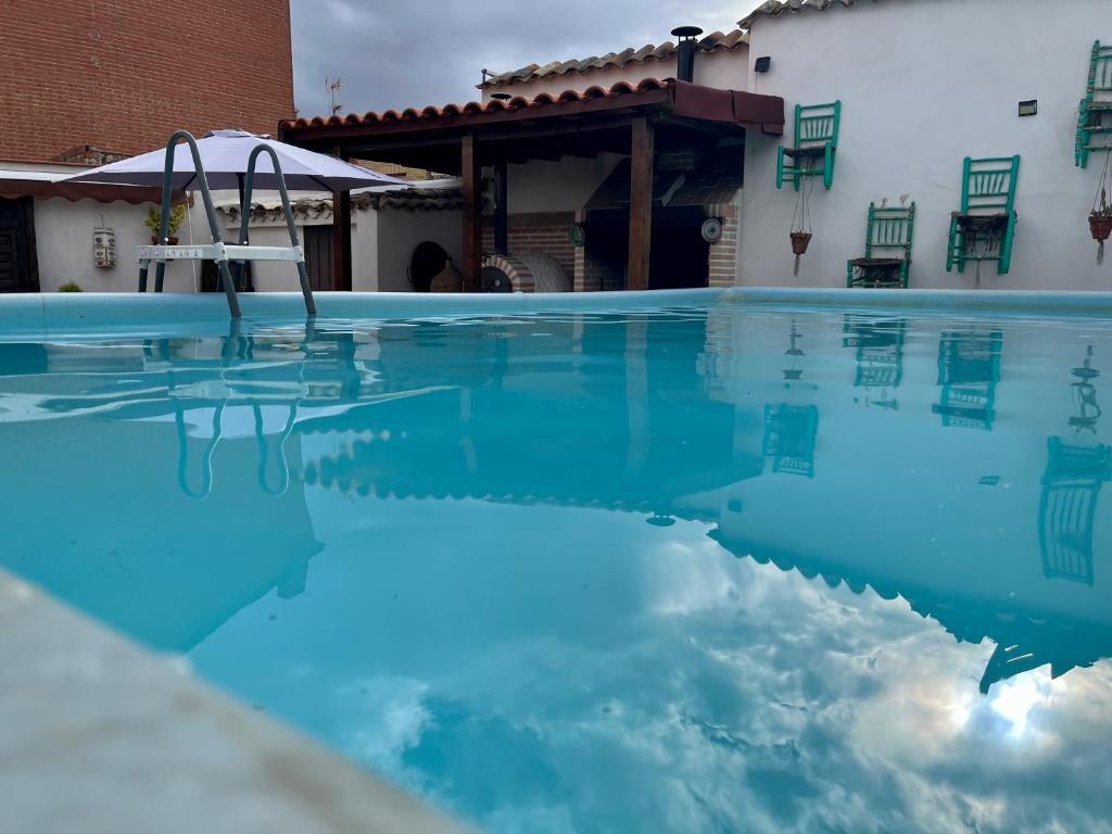 a swimming pool with blue water in front of a house at Casa El tio Daniel,,,,,,ahora con SPA in Bargas