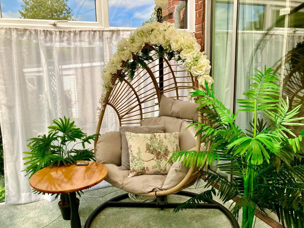 una silla de mimbre sentada en una habitación con plantas en The Little Acorn en Ben Rhydding