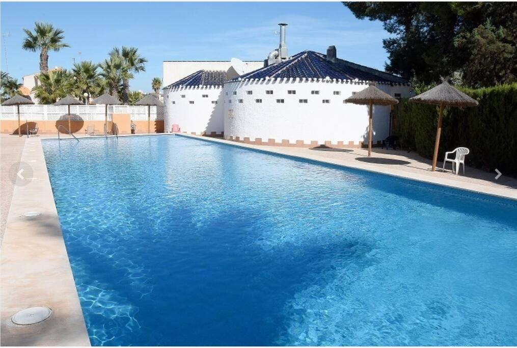 una gran piscina de agua azul frente a un edificio en VILLA ARTEP Lujoso apartamento con piscina comunitaria en Cartagena