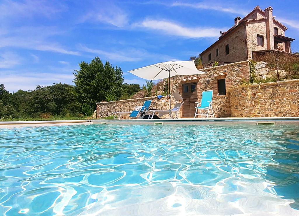 a swimming pool in front of a building with a house at Podere San Selvatico in Città della Pieve