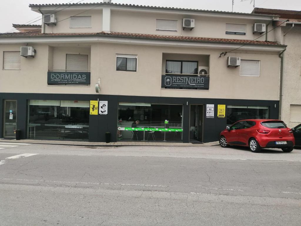 une voiture rouge garée devant un bâtiment dans l'établissement Restaurante e Residencial O Resineiro, à Vidago