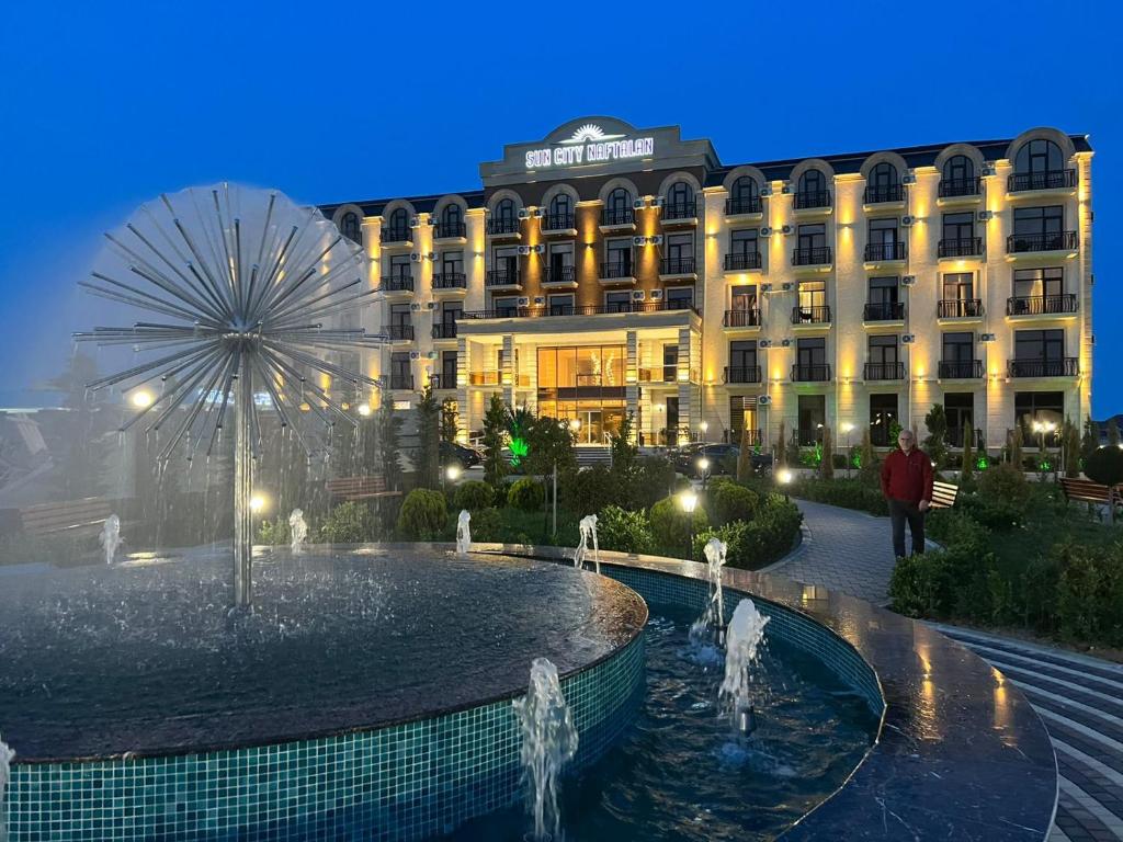 ein Hotel mit einem Brunnen vor einem Gebäude in der Unterkunft Sun City Hotel & Spa Naftalan in Naftalan