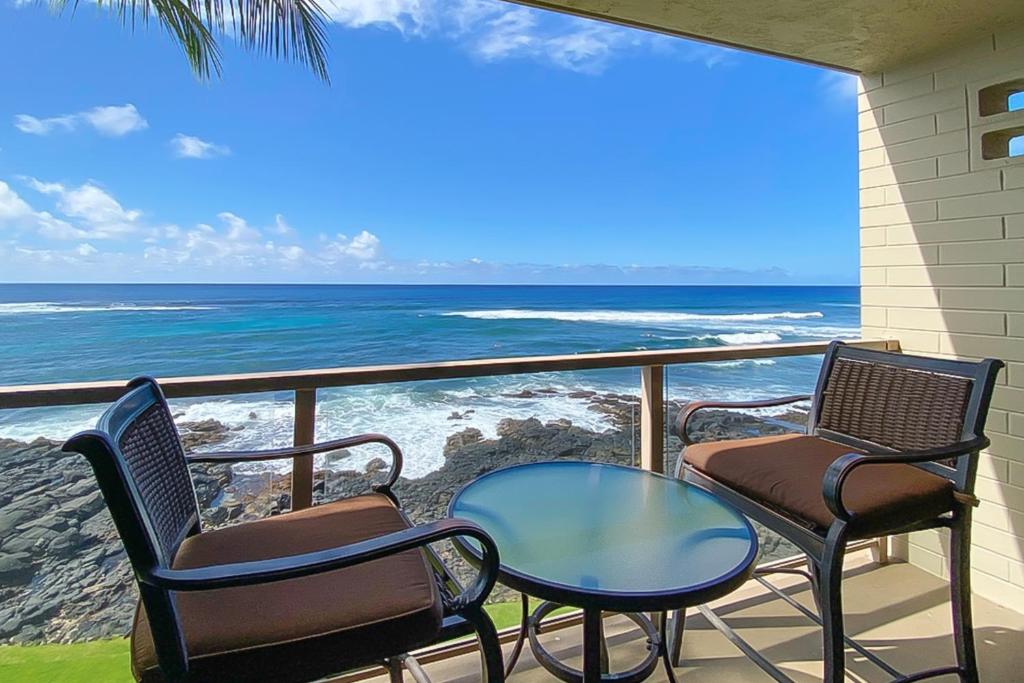 a balcony with chairs and a table and the ocean at Kuhio Shores 316 in Koloa