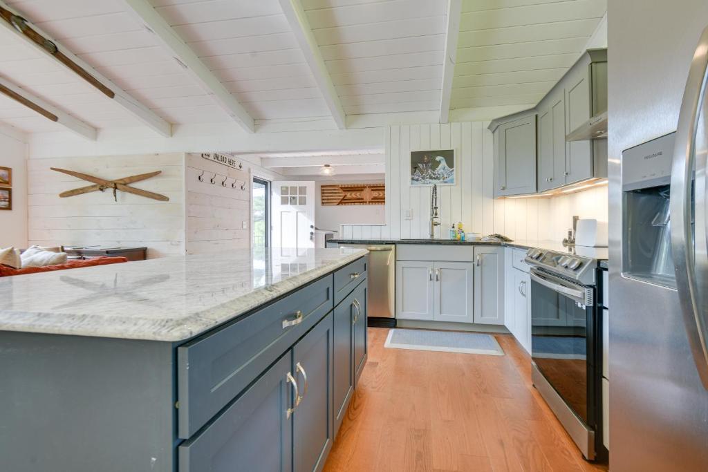 a large kitchen with blue cabinets and white appliances at Gilford Vacation Rental with Lake Access and Mtn Views in Gilford