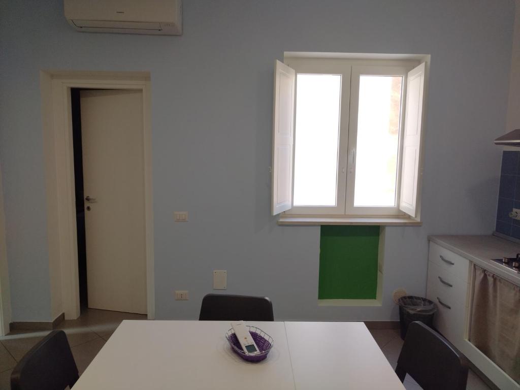 a kitchen with a white table and a window at LA REGGIA APARTMENTS MILAZZO in Milazzo