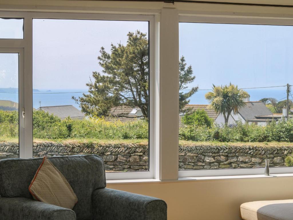 a living room with three windows and a couch at Seaport Lodge in Mawgan Porth