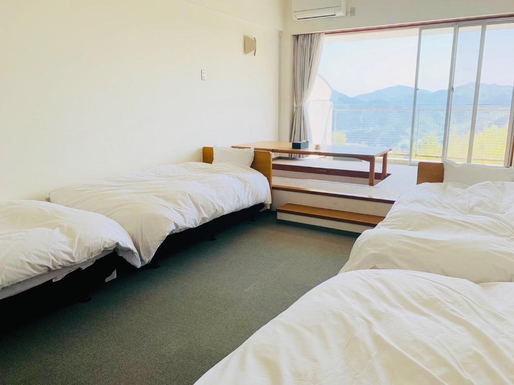 Habitación con 3 camas, mesa y ventana en Starry Sky and Sea of Clouds Hotel Terrace Resort - Vacation STAY 75160v, en Takeda