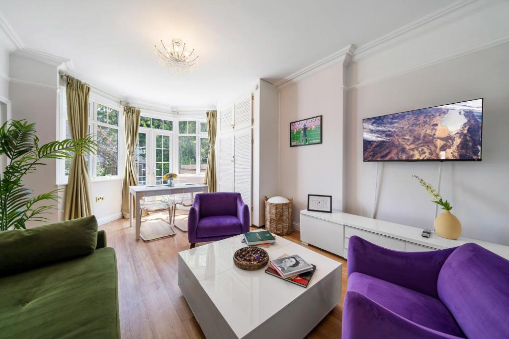 een woonkamer met een paarse bank en een tafel bij Lovely garden apartment in Wimbledon Town Centre with private parking by Wimbledon Holiday Lets in Londen