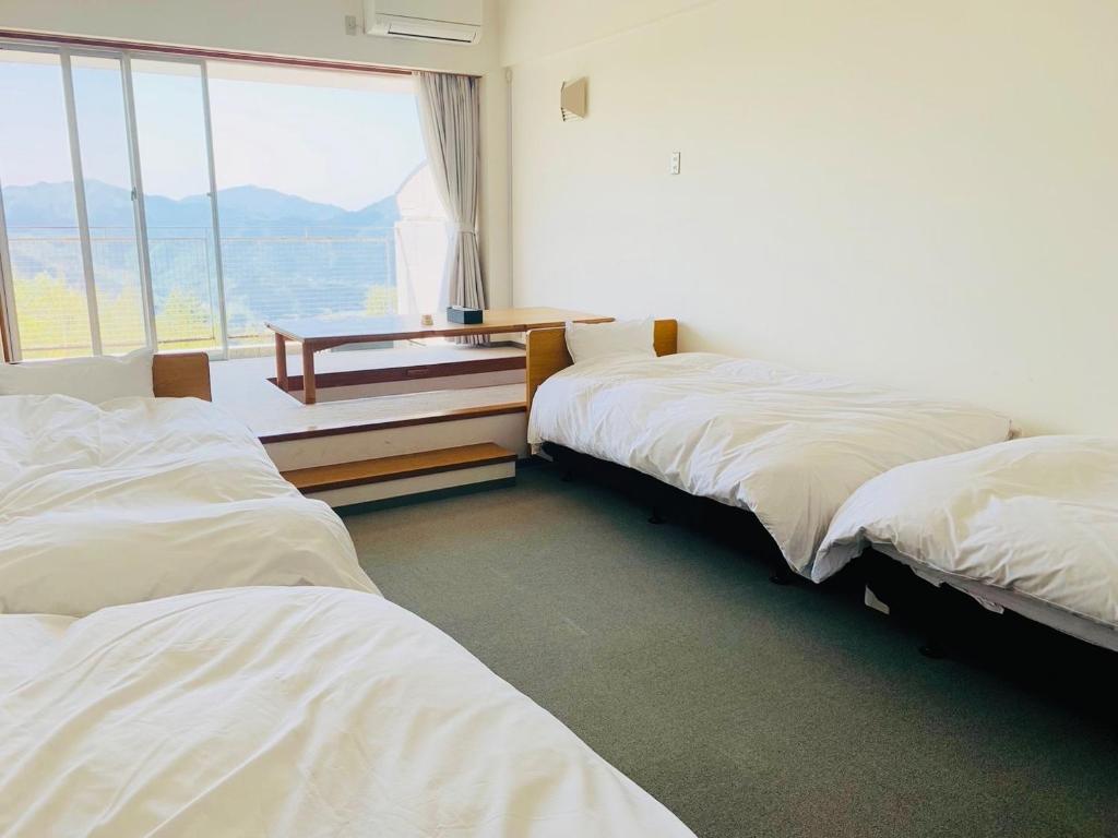 - 2 lits dans une chambre avec une table et une fenêtre dans l'établissement Starry Sky and Sea of Clouds Hotel Terrace Resort - Vacation STAY 75154v, à Takeda