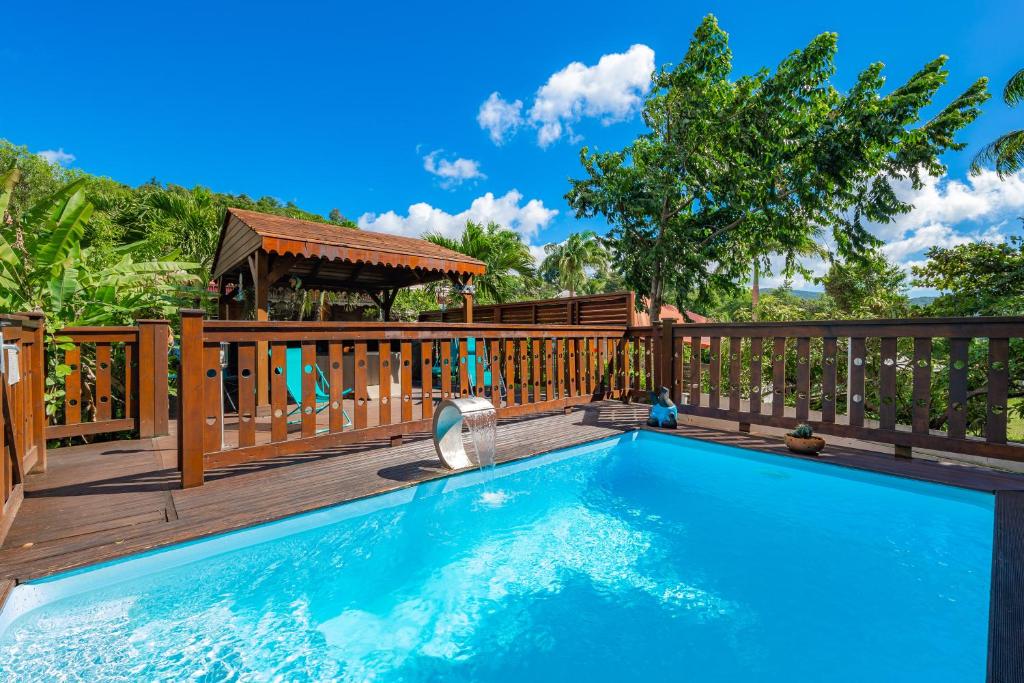 een zwembad op een houten terras met een speeltuin bij Blue Kaz Caraïb in Pointe-Noire