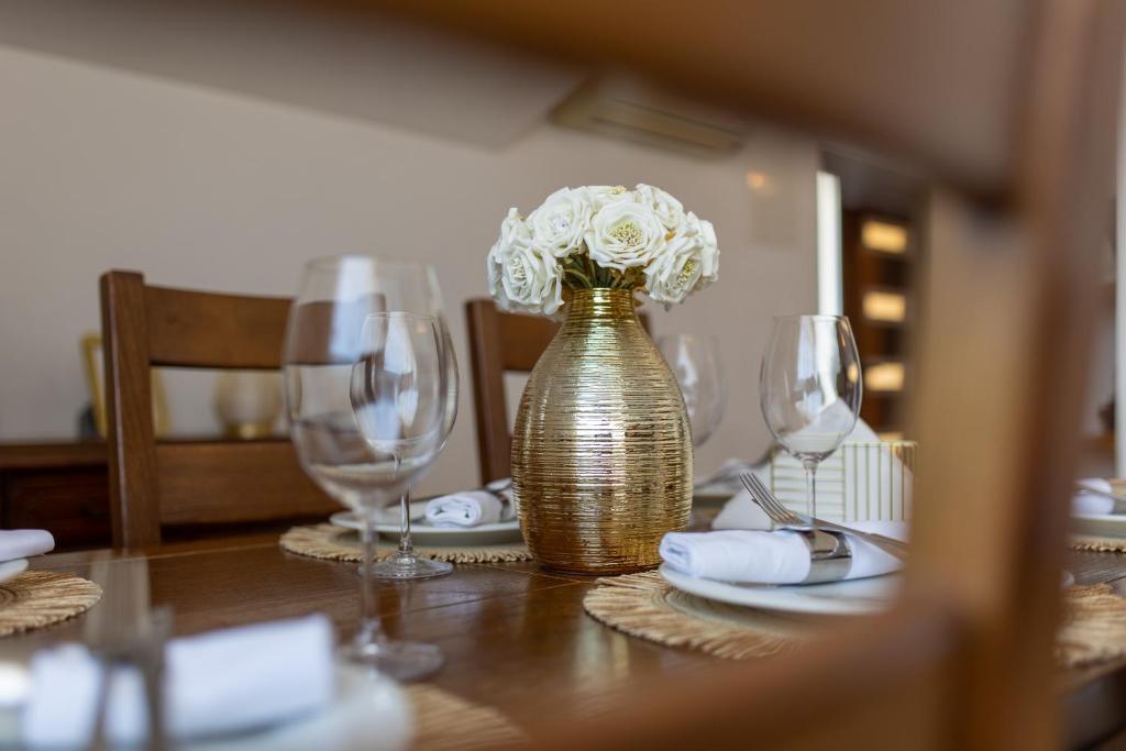 a table with a gold vase with white flowers in it at Apartments Vranjić in Trogir