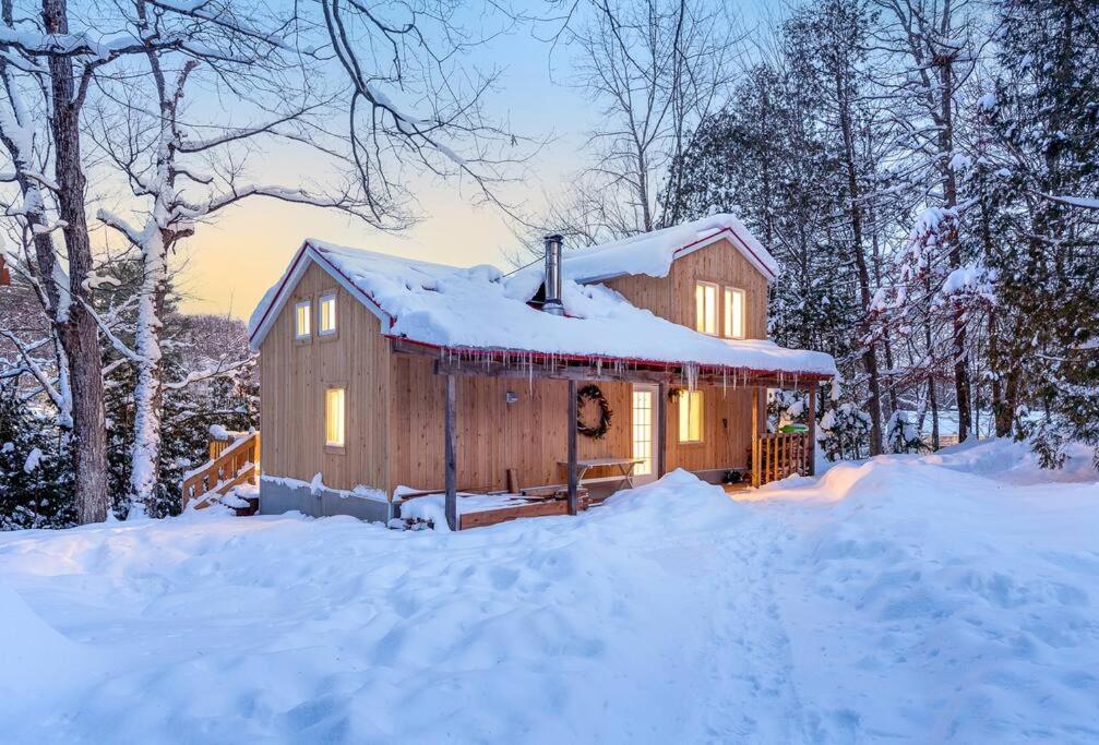 Cabaña de madera con nieve en el suelo en Nature et tranquilité à une heure de Montréal, vue sur le lac en Saint-Calixte