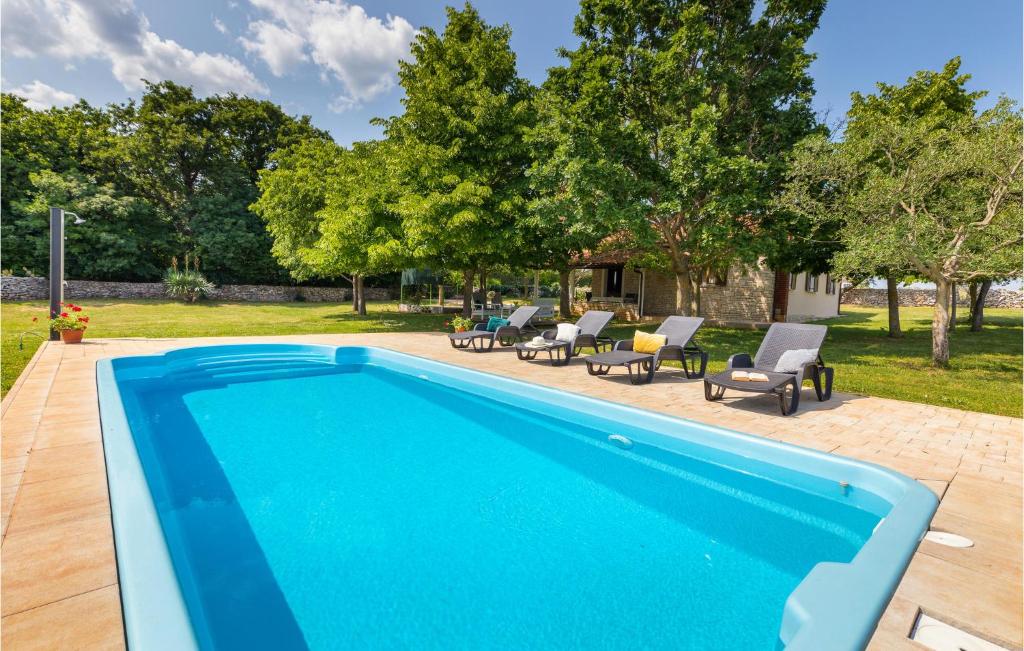 uma piscina azul com cadeiras e árvores em Awesome Home In Svetvincenat With Outdoor Swimming Pool, 2 Bedrooms And Wifi em Svetvincenat
