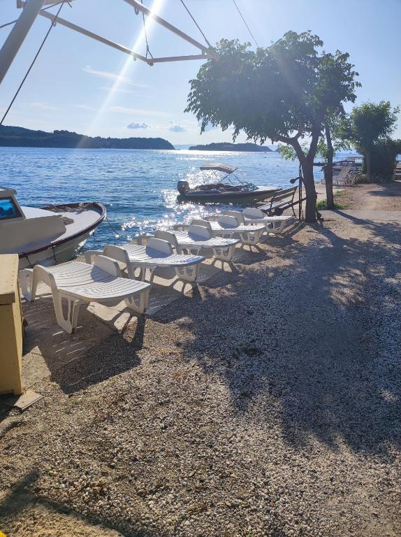 eine Reihe von Tischen und Stühlen an einem Strand in der Nähe des Wassers in der Unterkunft Apartmani Kordić in Rab