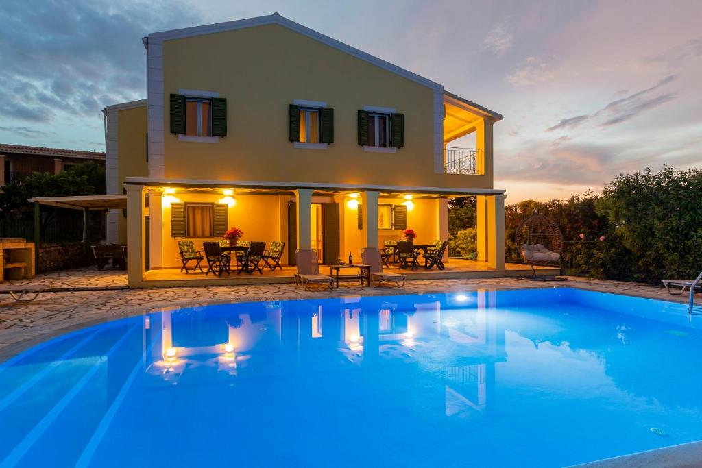 a villa with a swimming pool in front of a house at Villa Charchala in Kassiopi