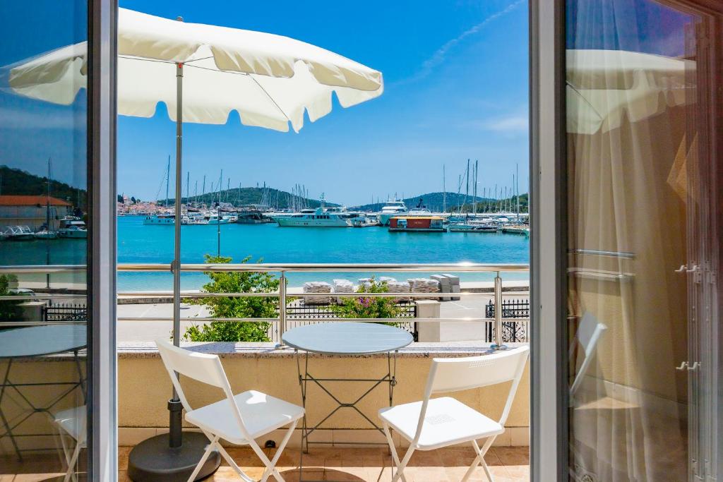 een tafel en stoelen op een balkon met uitzicht op het water bij Apartments Mikulić in Rogoznica