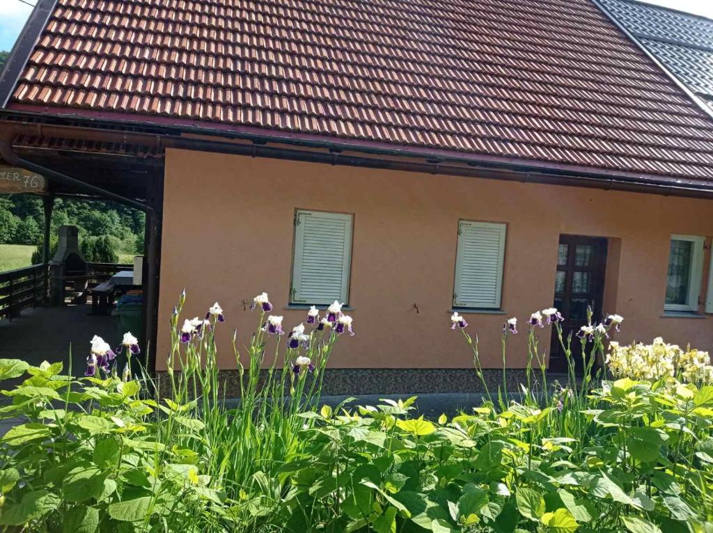 un jardín con flores frente a una casa en Apartman Rozmari en Lokve