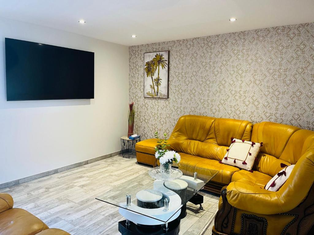 een woonkamer met een gele bank en een flatscreen-tv bij Charmante maison à Blois - Terrasse privée - 8 pers in Blois