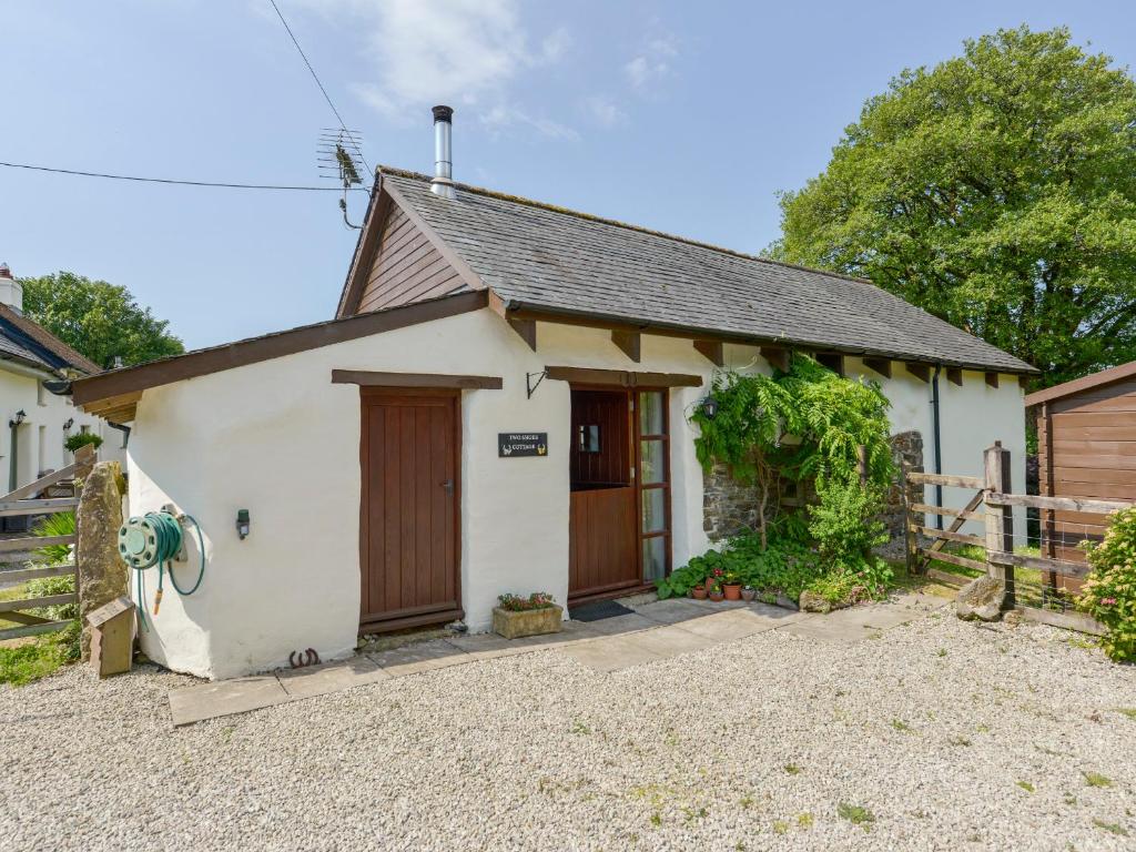 a small white house with a wooden door at Two Shoes Cottage in Okehampton