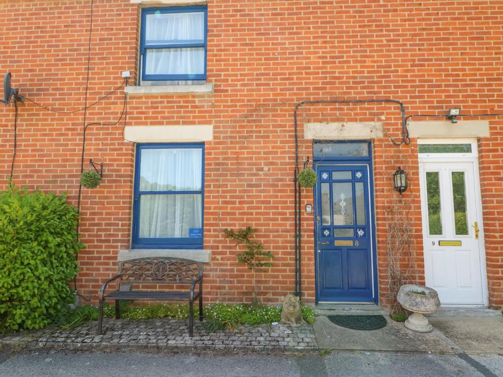 a brick house with a blue door and a bench at Studland Cottage in Swanage