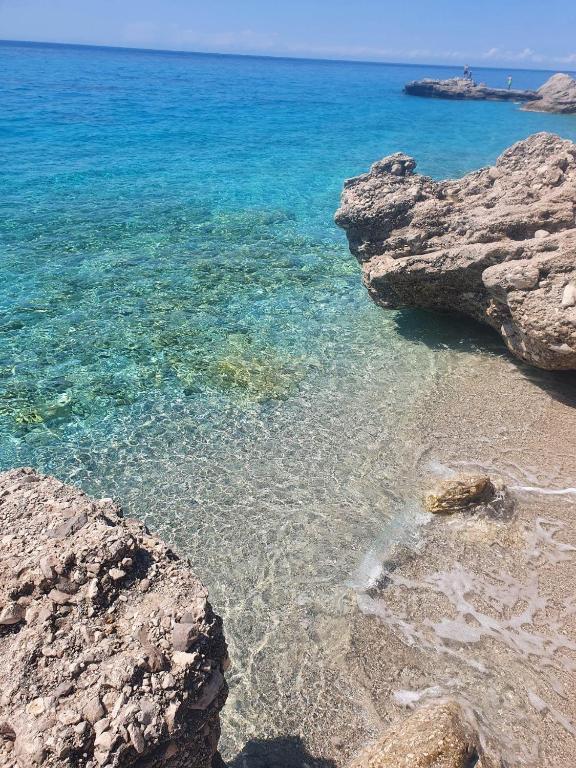 a beach with rocks and clear blue water at Endless blue Apartments in Dhërmi