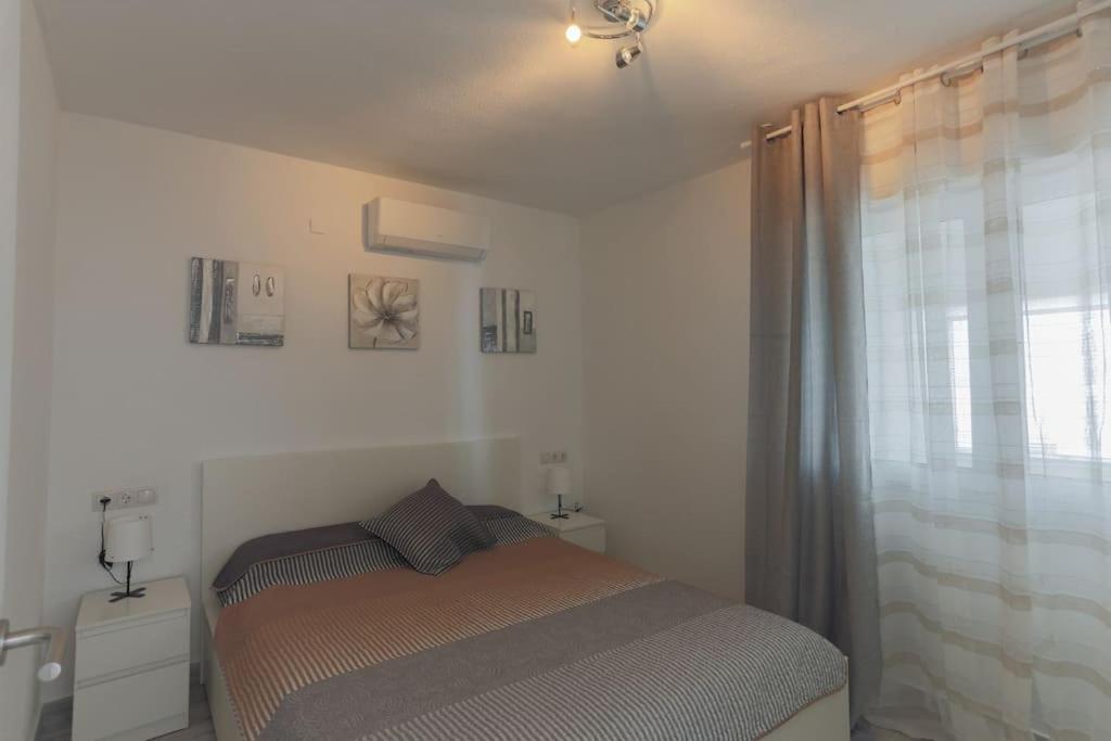a small bedroom with a bed and a window at Apartamentos de Benidorm, playa Poniente, España in Benidorm