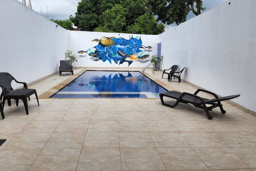 una piscina con sedie e un dipinto sul muro di Casa Villa Palmitas - Tocaima a Tocaima