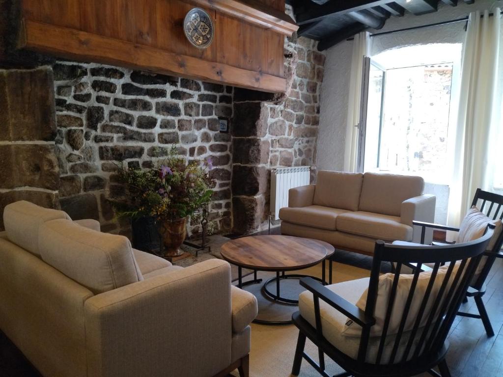 salon z krzesłami, stołem i ceglaną ścianą w obiekcie Gîte de la Tournelle w mieście Pradelles