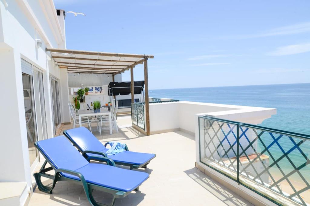 a balcony with two blue chairs and the ocean at Sunset Paradise in Armação de Pêra