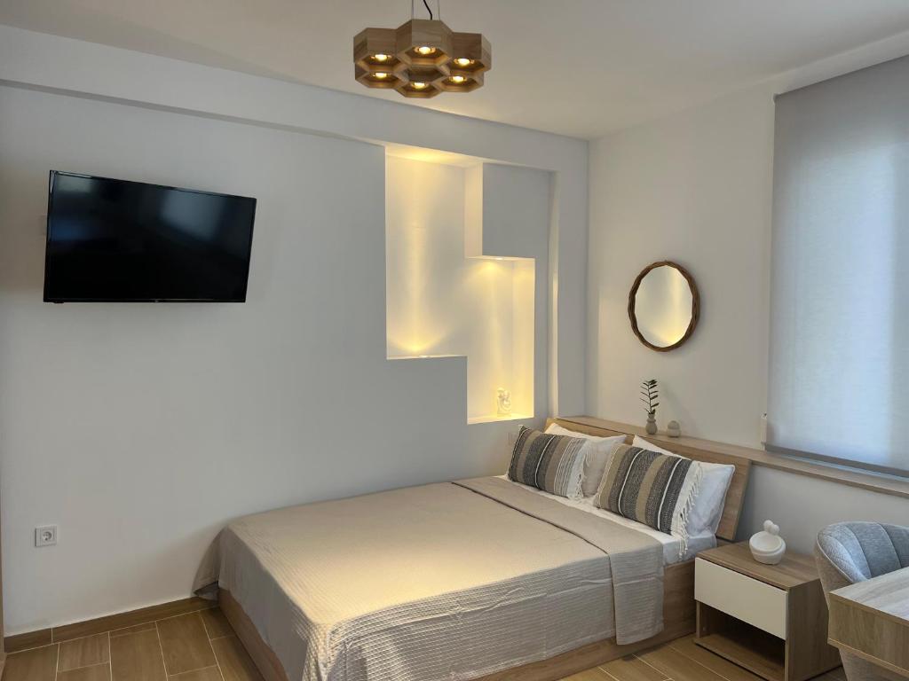 a bedroom with a bed and a flat screen tv at Calm Joy & J - Bee in Ermoupoli