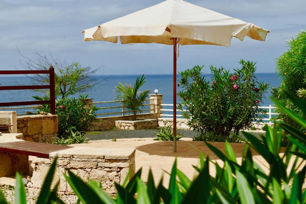 un paraguas sentado en una mesa junto al océano en Casita Solemar direkt am Atlantik en Calheta Do Maio