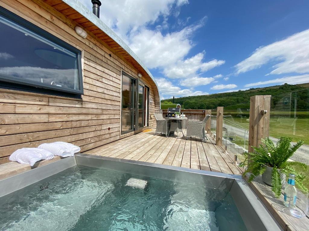 a swimming pool next to a wooden house with a deck at Low Longlands in Cartmel